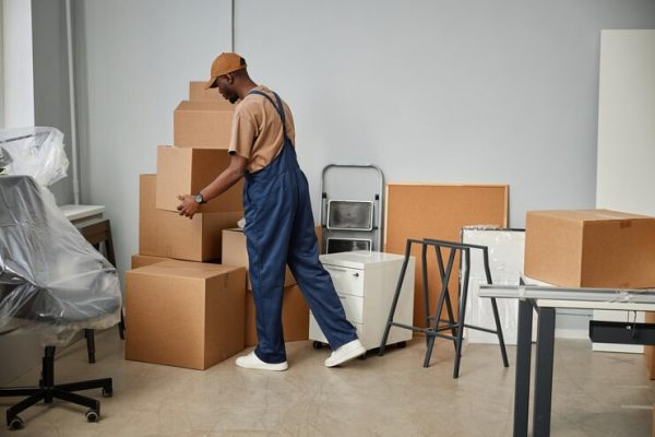 Worker arranging boxes and equipment, getting ready for a commercial moving operation.