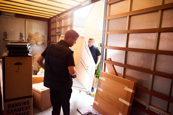 Movers carefully load furniture and boxes into a moving truck during a residential relocation.