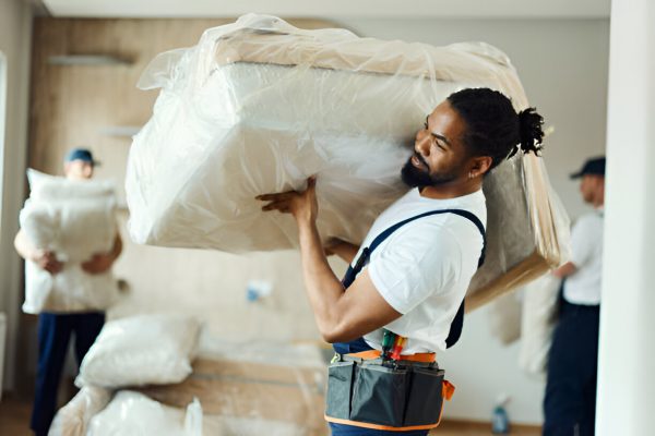 Professional mover carefully handling wrapped furniture during a residential relocation.