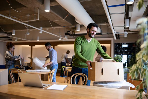 Employees packing boxes and equipment during an organized office relocation process.