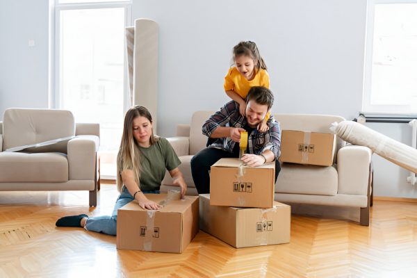 A happy family packs moving boxes together in their living room, preparing for a fresh new start.