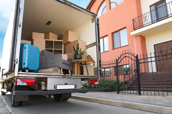 Moving truck packed with furniture and boxes parked outside a residential home on moving day.